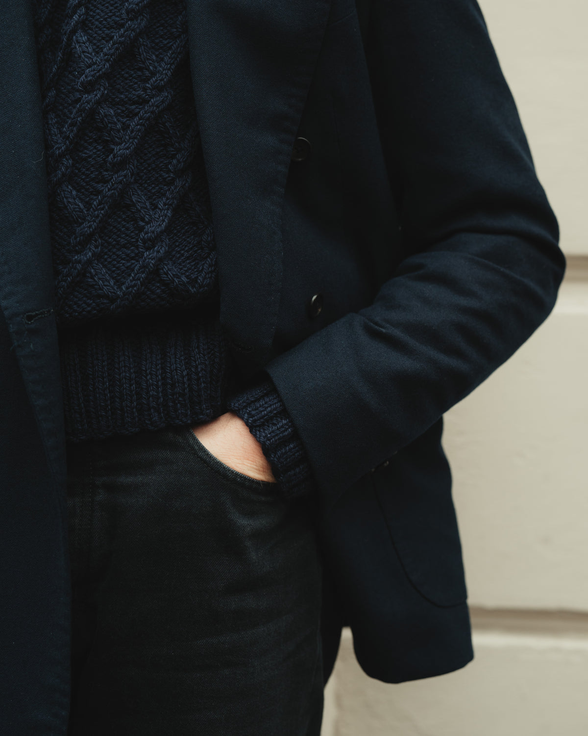 Detail of the generously ribbed hem and cuffs under a tailored jacket of the Navy Hand-Knitted Mariner by Rubato. 
