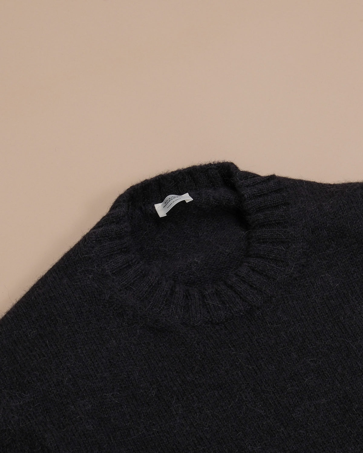 Detail of the ribbed neckline on the Nero Nonpareil Cortina Crewneck by Rubato. 